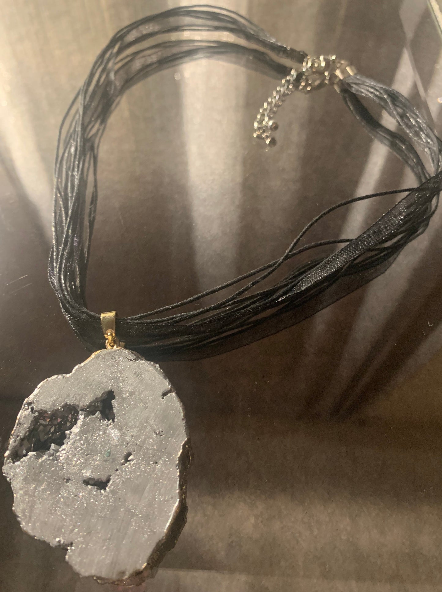 Necklace, Natural Cratered Pewter Stone framed in gold accented with 18" nylon ribbon and cord finished with lobster clasp and extension chain.
