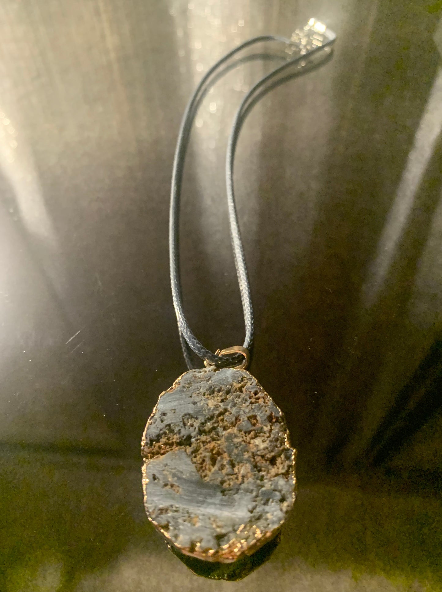 Necklace, Natural Pewter Cratered Stone framed in gold accented with 18" cord finished with lobster clasp and extension chain.